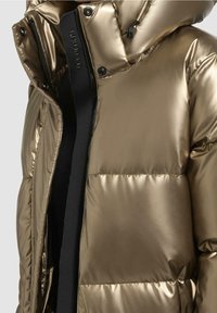 Goldfarbener Puffer-Jacke mit glänzender Oberfläche, gestepptem Design, abnehmbarem Kapuzen und schwarzem Reißverschluss, der einen modernen, gepolsterten Look bietet.