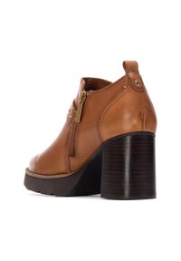 Stivaletto in pelle marrone con punta arrotondata, cerniera laterale e tacco alto spesso e texture. Finitura liscia con dettagli di cucitura sottili.