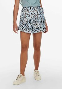 Svetle modré šortky s volánkem, s leopardím vzorem v černé a hnědé barvě. Kombinováno s bílými teniskami.
