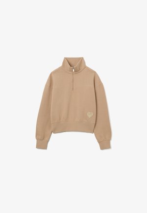 Felpa corta beige con colletto alto e zip a metà, caratterizzata da un logo a forma di cuore sul lato sinistro. Tessuto morbido e strutturato, maniche a vestibilità ampia.