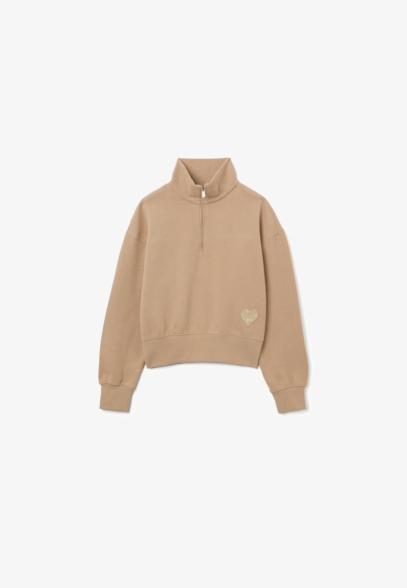 Felpa corta beige con colletto alto e zip a metà, caratterizzata da un logo a forma di cuore sul lato sinistro. Tessuto morbido e strutturato, maniche a vestibilità ampia.