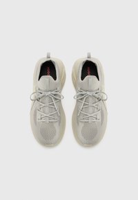 Light grey sneakers made of mesh material and rubber. Features a lace-up design, padded collar, and a textured sole. Brand name visible inside.
