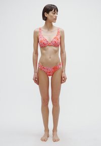 Bikinisæt i pink med blomsterprint. Indeholder en trekants-BH med justerbare stropper og lavtsiddende underdel. Glat, tætsiddende materiale.