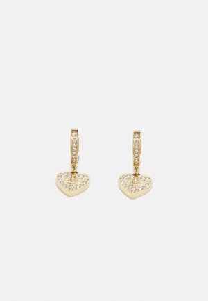 Boucles d'oreilles en or avec des pendentifs en forme de cœur ornés de cristaux transparents, attachés à des fermoirs en forme de créole. Surface métallique lisse avec une finition brillante.