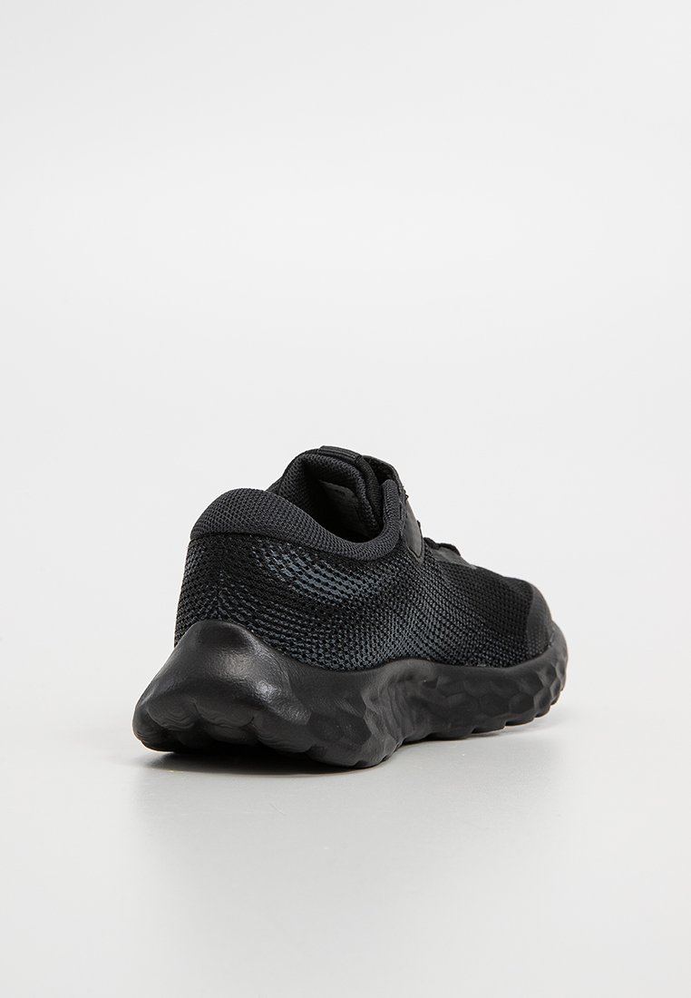 Chaussure de sport noire avec une tige en maille texturée et une semelle épaisse et rembourrée. Talon arrondi et design minimaliste. Pas de marque visible.
