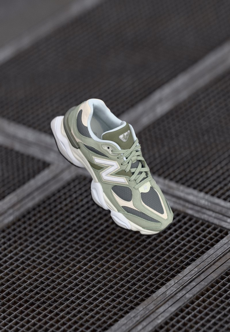 Green and beige running shoe with mesh and synthetic materials, featuring a rounded shape, textured accents, and a prominent logo on the side.