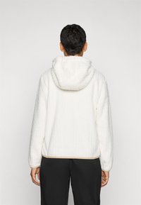 Witte, gestructureerde fleece hoodie met een capuchon, lange mouwen en een beige zoom. Zicht van achteren, met de stiksels en pasvorm goed in beeld.