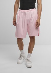 Lyserøde træningsshorts lavet af glat, letvægtsstof, med elastisk talje og sideslidser for nem bevægelse.