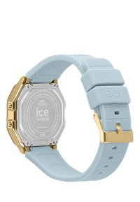 Boîtier de montre octagonal en acier inoxydable argenté avec un bracelet en silicone bleu clair et des accessoires en métal doré. Résistant à l'eau jusqu'à 30 mètres.
