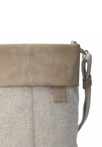 Borsa di tessuto grigia con una parte superiore in pelle beige piegata. Presenta una tracolla, un piccolo logo e cuciture visibili lungo le cuciture.