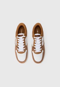 Braune und weiße Sneaker mit einem Obermaterial aus glattem Leder und Textil, ausgestattet mit perforierten Akzenten, weißen Schnürsenkeln und einem runden Zehendesign.