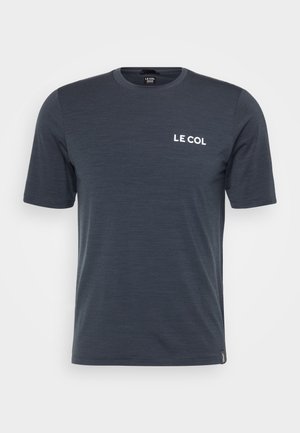 Tumedal sinise lühikeste varrukatega T-särk, mis on valmistatud pehmest kangast. Omab ümardatud kaelust ja valget "LE COL" logo vasakul rinnal.