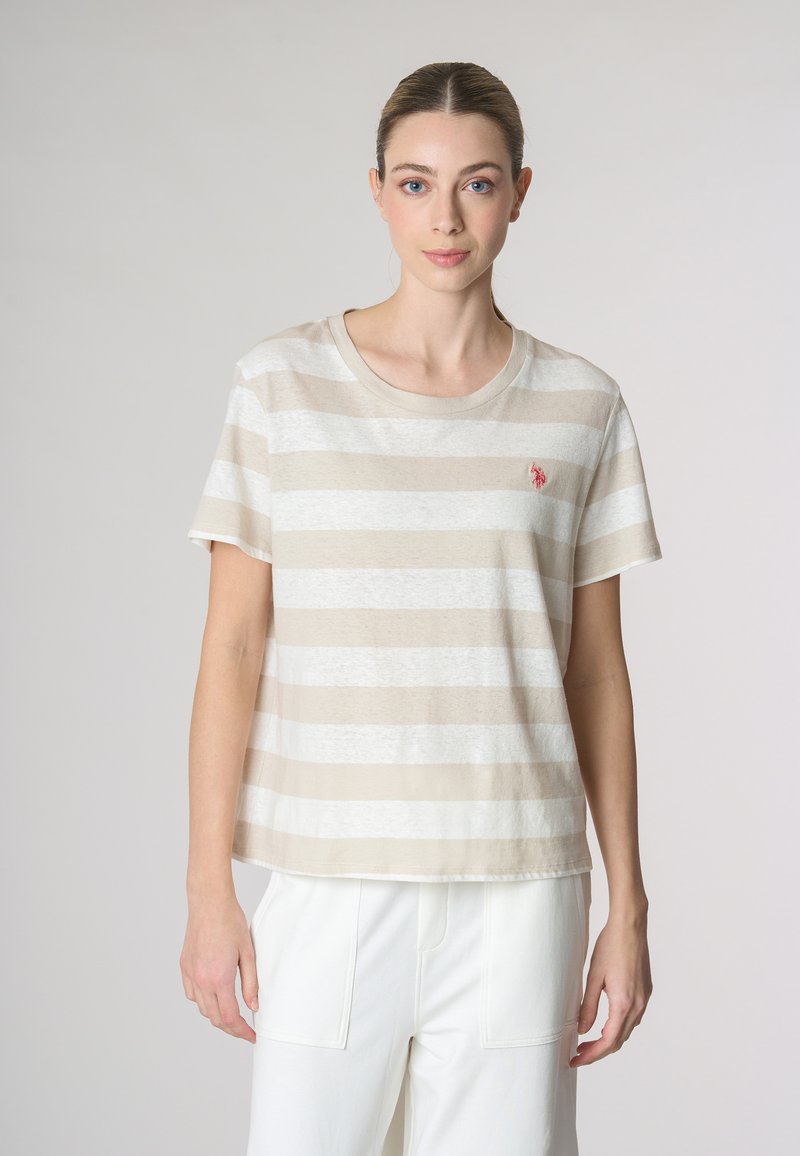 T-shirt a righe beige e bianche con collo tondo, maniche corte e un piccolo logo ricamato sul lato sinistro del petto. Materiale in cotone morbido.