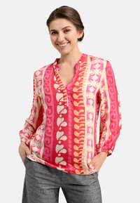 Colorful, patterned blouse in pink, cream, and orange. Long sleeves, V-neck with a button placket, relaxed fit. Soft, smooth fabric.