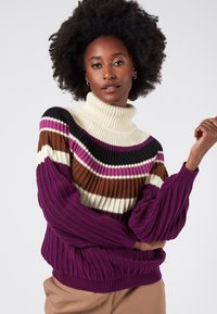 Färgglad stickad tröja med polokrage, horisontella ränder i lila, svart, brun och krämfärgad, med ribbad textur och mudd.