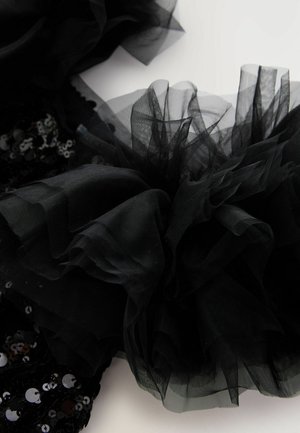 Tessuto di tulle nero disposto in un design arruffato, caratterizzato da paillettes circolari di dimensioni variabili, che creano un aspetto strutturato e stratificato.