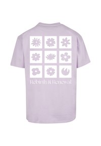 Lilla bomulds t-shirt med et grafisk tryk af ni blomsterdesigns i hvid. Teksten nedenfor lyder "Genfødsel & Fornyelse." Korte ærmer og rund halsudskæring.
