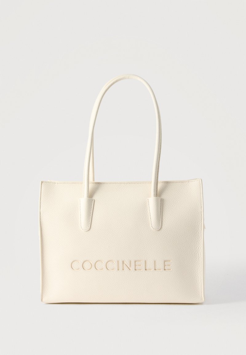 Τσάντα tote από δέρμα σε κρεμ χρώμα με διπλές λαβές και το λογότυπο "COCCINELLE" ανάγλυφο μπροστά.