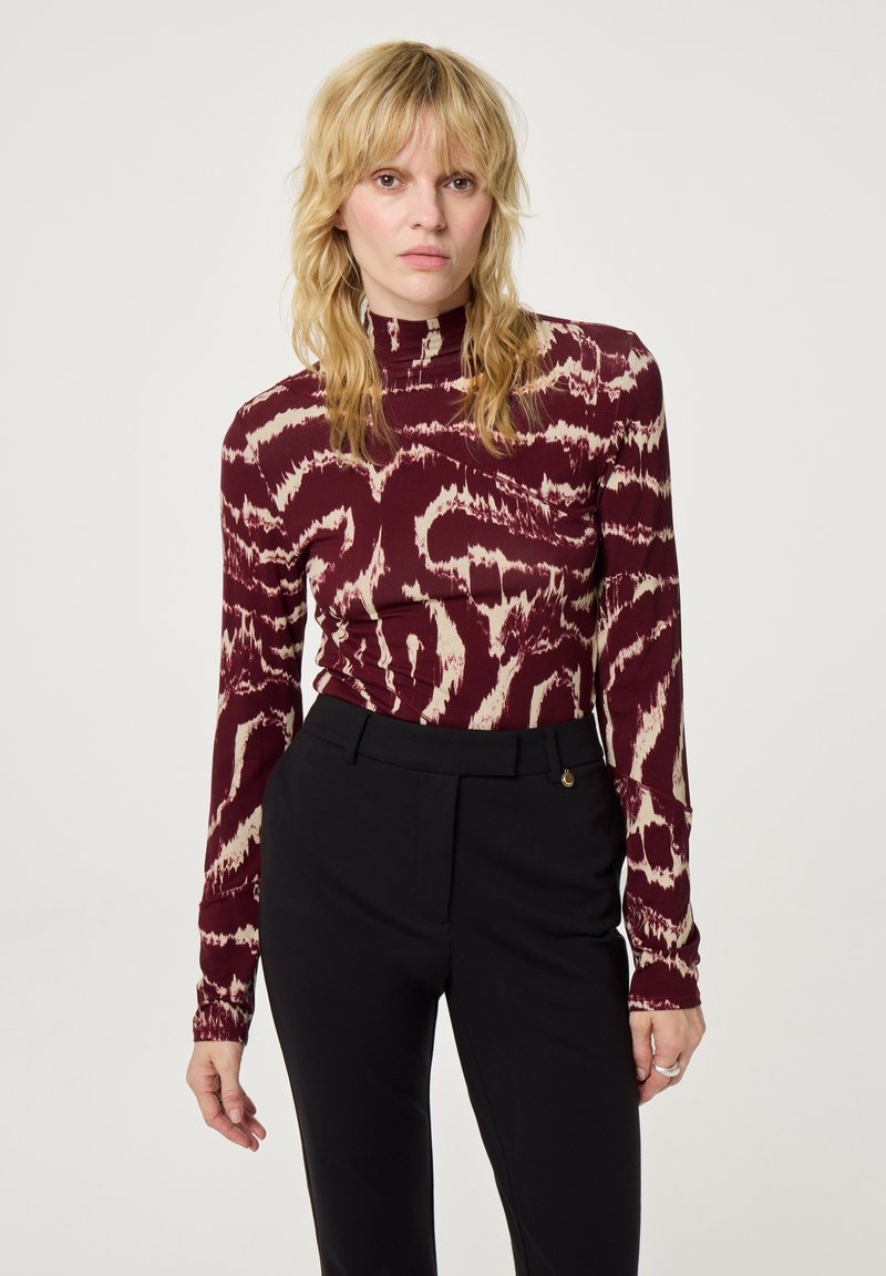 Bordeaux lange mouwen top met een abstract crèmekleurig patroon, hoge hals en aansluitend ontwerp, gecombineerd met op maat gemaakte zwarte broeken.