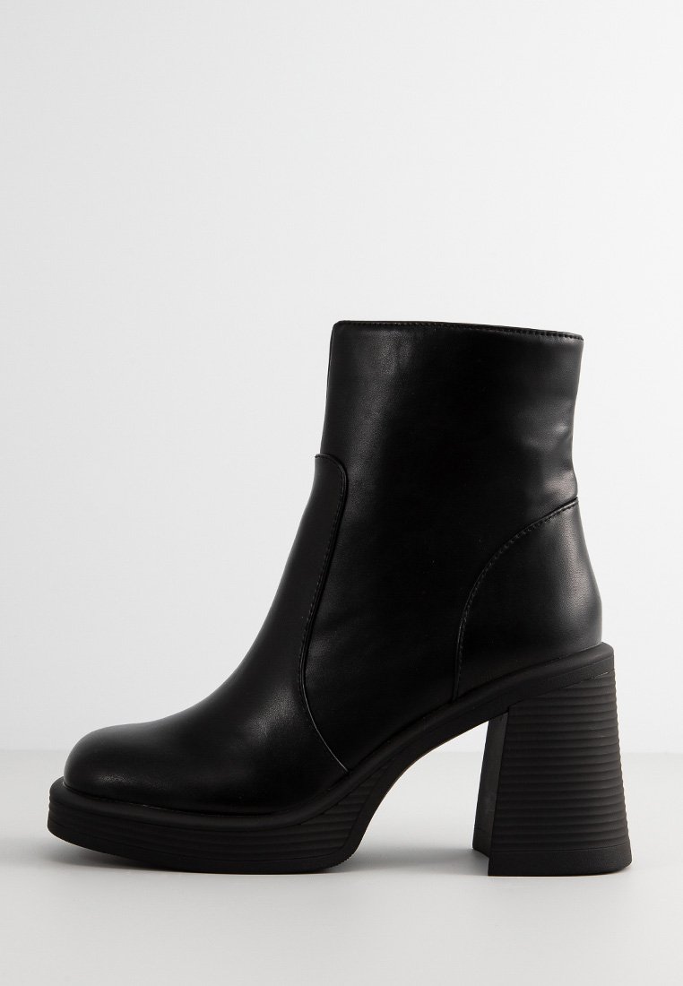 Bottines en cuir noir avec un bout arrondi, surface lisse et talon bloc texturé. Équipées d'un panneau latéral élastique pour un enfilage facile.