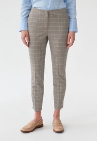 Pantalons à carreaux dans des tons beiges et marron, coupe ajustée, fabriqués en tissu texturé. Présentent une taille mi-haute et des poches latérales discrètes.