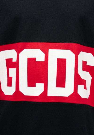 Sort stof med en vandret rød stribe med store hvide blokbogstaver, der staver "GCDS".