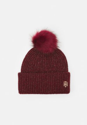 Bonnet tricoté bordeaux avec un revers plié, un pompon duveteux sur le dessus, et un petit logo double T brodé sur le bord.