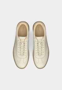 Cream-colored leather sneakers with a round toe, beige laces, and rubber gum sole. Notable GANT branding on the tongue and side.