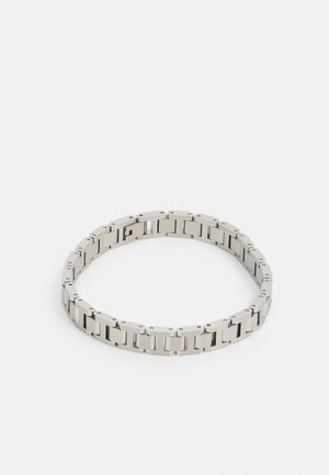 Zilveren metalen armband met rechthoekige schakeltonen, een gepolijste afwerking en kleine ronde accenten, ontworpen voor een nauwsluitende pasvorm om de pols.