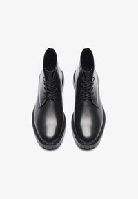 Botas de cuero negro hasta el tobillo con un acabado suave, punta redondeada y cordones en la parte delantera. Presentan una suela gruesa con patrones texturizados para mayor agarre.