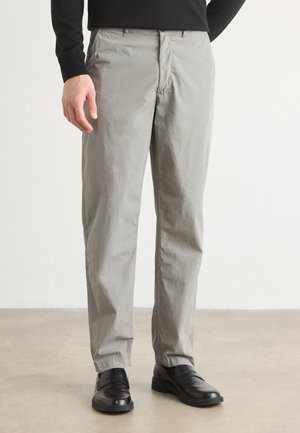 Pantaloni gri deschis, confecționați dintr-un material moale, texturat. Prezintă un design cu picior drept, buzunare frontale și închidere cu fermoar. Purtați cu pantofi negri.