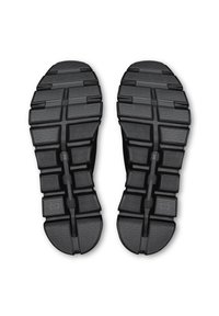 Schwarze Laufsohlen mit einem strukturierten, segmentierten Design, das auffällige Profilstollen und geprägte Markendetails aufweist und so Grip und Flexibilität verbessert.