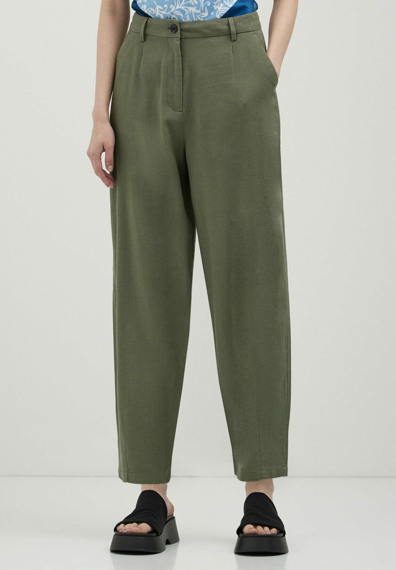 Pantalons en lin vert olive à coupe décontractée, dotés de deux poches latérales, d'une fermeture à bouton et d'une texture lisse. Associés à des sandales à talons blocs noires.