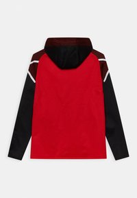 Rote und schwarze Jacke mit Kapuze, die einfarbig blockiertes Design, strukturierte Schulterakzente und kontrastierende weiße Streifen entlang der Nähte aufweist.