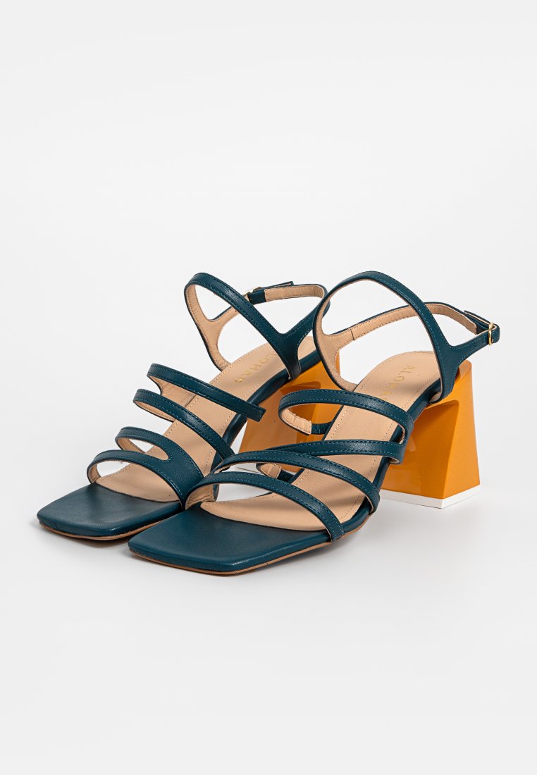 Sandales ouvertes à bout carré en teal, avec des talons carrés orange vif, dotées de brides autour des chevilles et de multiples fines bandes sur le dessus des pieds.