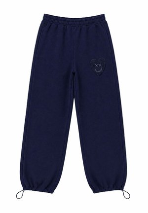 Pantalones deportivos azul marino con cintura y puños elásticos, con un parche texturizado en forma de corazón con ojos tachados y una sonrisa en la parte superior de la pierna.