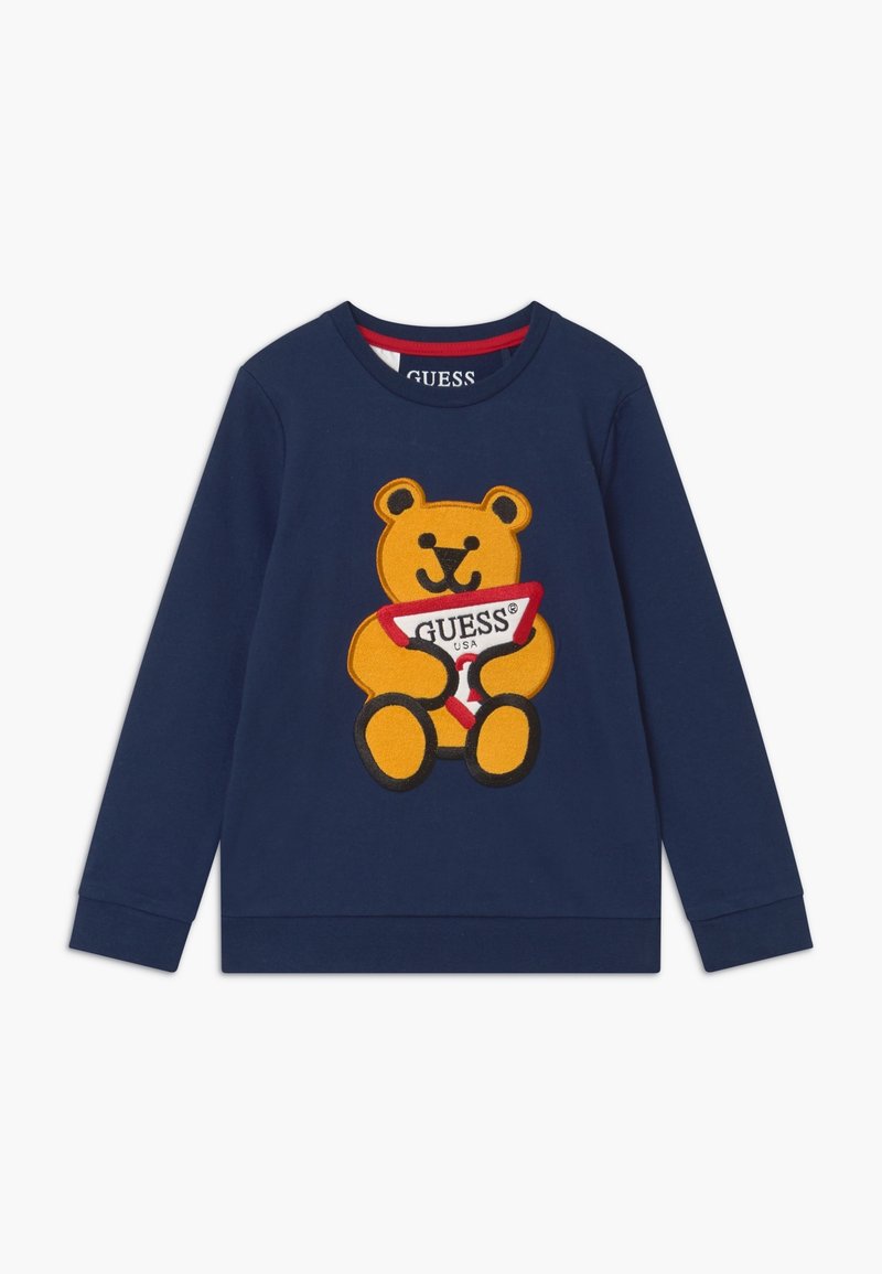 Marinefarbener Sweatshirt mit einer großen gelben Teddybär-Grafik, der ein rot-weißes "GUESS"-Schild hält, aus weichem Baumwollmaterial gefertigt.