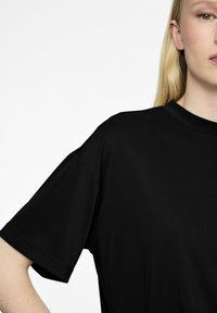 T-shirt nero a maniche corte con scollo rotondo, texture liscia e vestibilità comoda. Dettagli delle cuciture visibili sulle maniche.