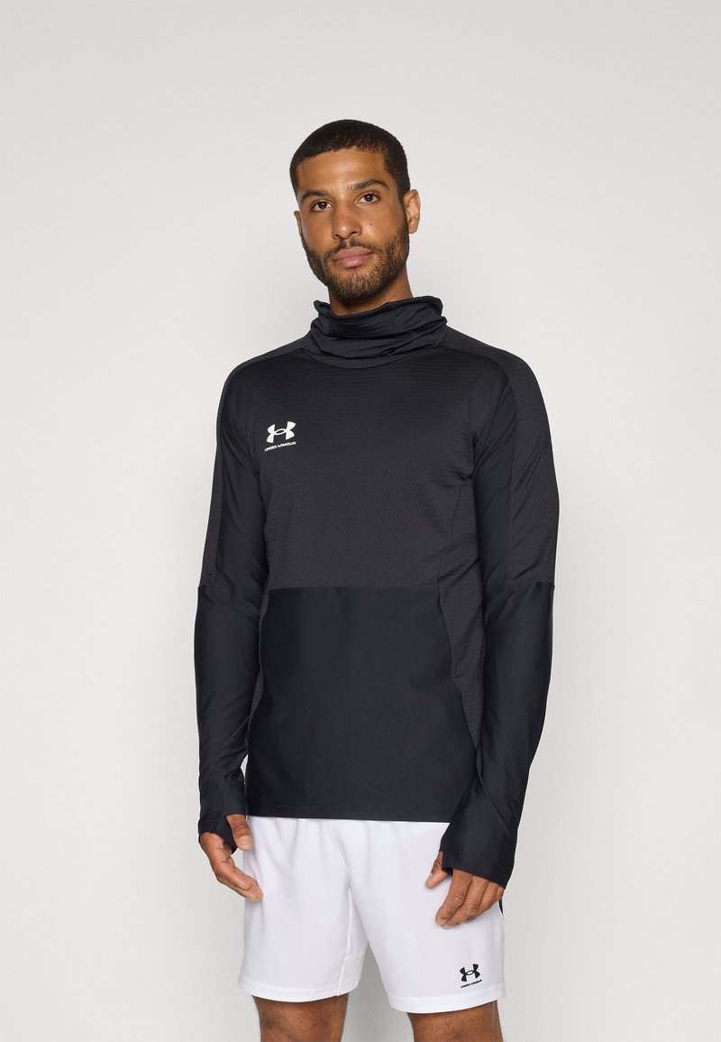 Black long-sleeve athletic top with a high collar, textured fabric, and thumbholes. Features a white Under Armour logo on the chest.