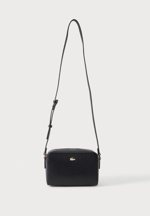 Sac bandoulière rectangulaire noir avec bandoulière fine réglable et petit logo crocodile doré au centre avant.