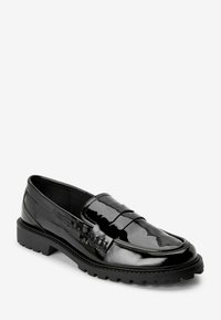 Mocasín de charol negro con suela de goma texturizada baja y un diseño clásico de tira para monedas. Superficie suave con un brillo sutil.