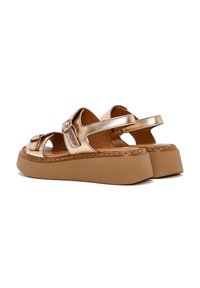 Sandali bronzo metallizzato con doppie cinghie regolabili, una suola a piattaforma contornata di colore nocciola e dettagli di cucitura visibili lungo il bordo.