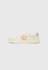 White sneakers with a beige star logo, leather and suede material, round toe, lace-up design, and a textured rubber sole.
