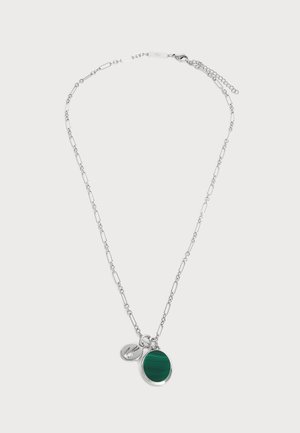 Collier chaîne en argent avec des maillons allongés, avec un pendentif rond en pierre verte et un petit charm en forme d’étiquette en argent.