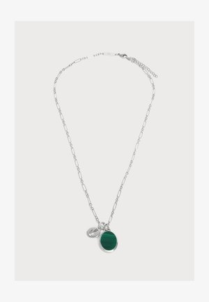 Collier chaîne en argent avec des maillons allongés, avec un pendentif rond en pierre verte et un petit charm en forme d’étiquette en argent.