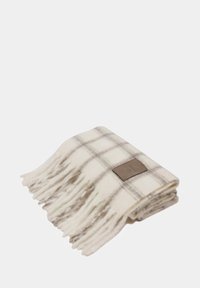 Coperta in lana a quadri bianca con strisce grigie, con bordi frangiati e un'etichetta marrone. Texture morbida e forma rettangolare.