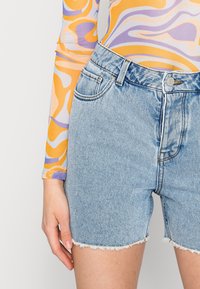 Vaaleansiniset farkkushortsit, joissa on risareuna, korkea vyötärö, klassinen viisi-taskumalli ja hienovarainen haalistunut pinta.