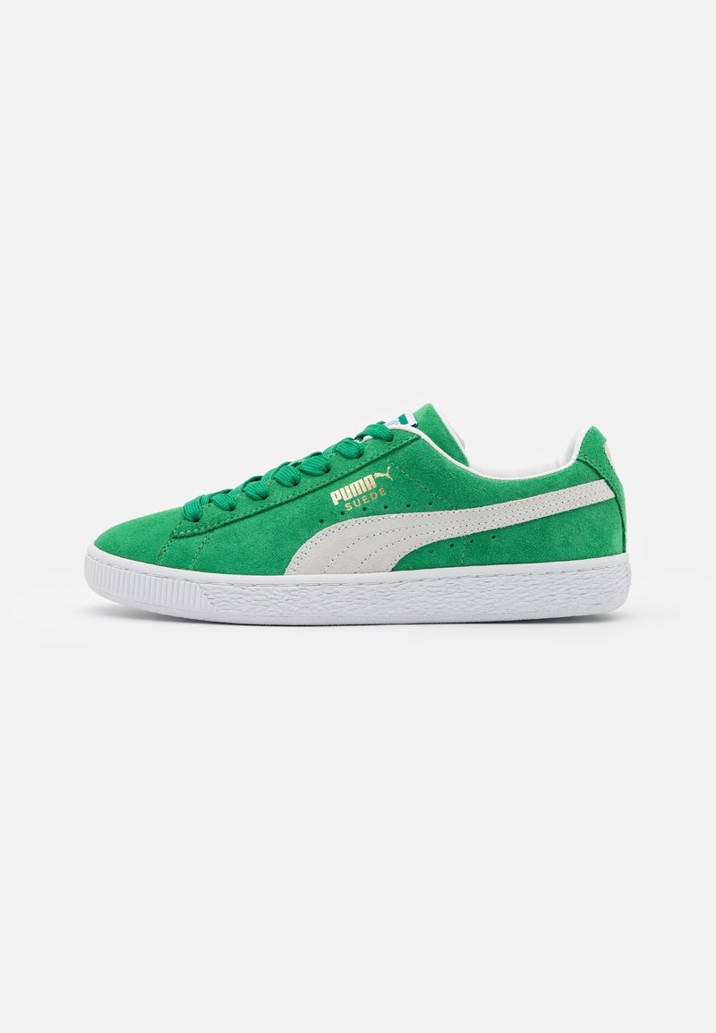 Baskets en daim vert Puma avec bande latérale blanche, semelle blanche, lacets verts et logo Puma Suede doré sur le côté.