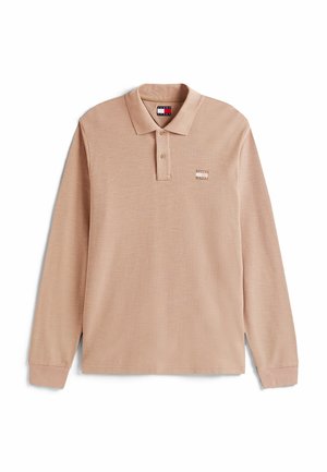 Camisa polo de manga larga en color beige claro, con una tela texturizada, un cuello clásico, una tapeta de dos botones y un pequeño logotipo en el pecho.