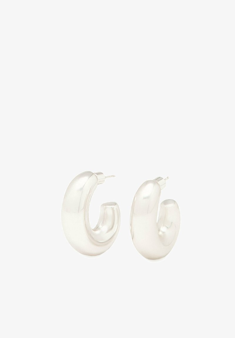 Silverfärgade hoopsörhängen med en kurvig, skulptural design; glänsande, slät yta; säkra stiftbackar; modern och elegant form.